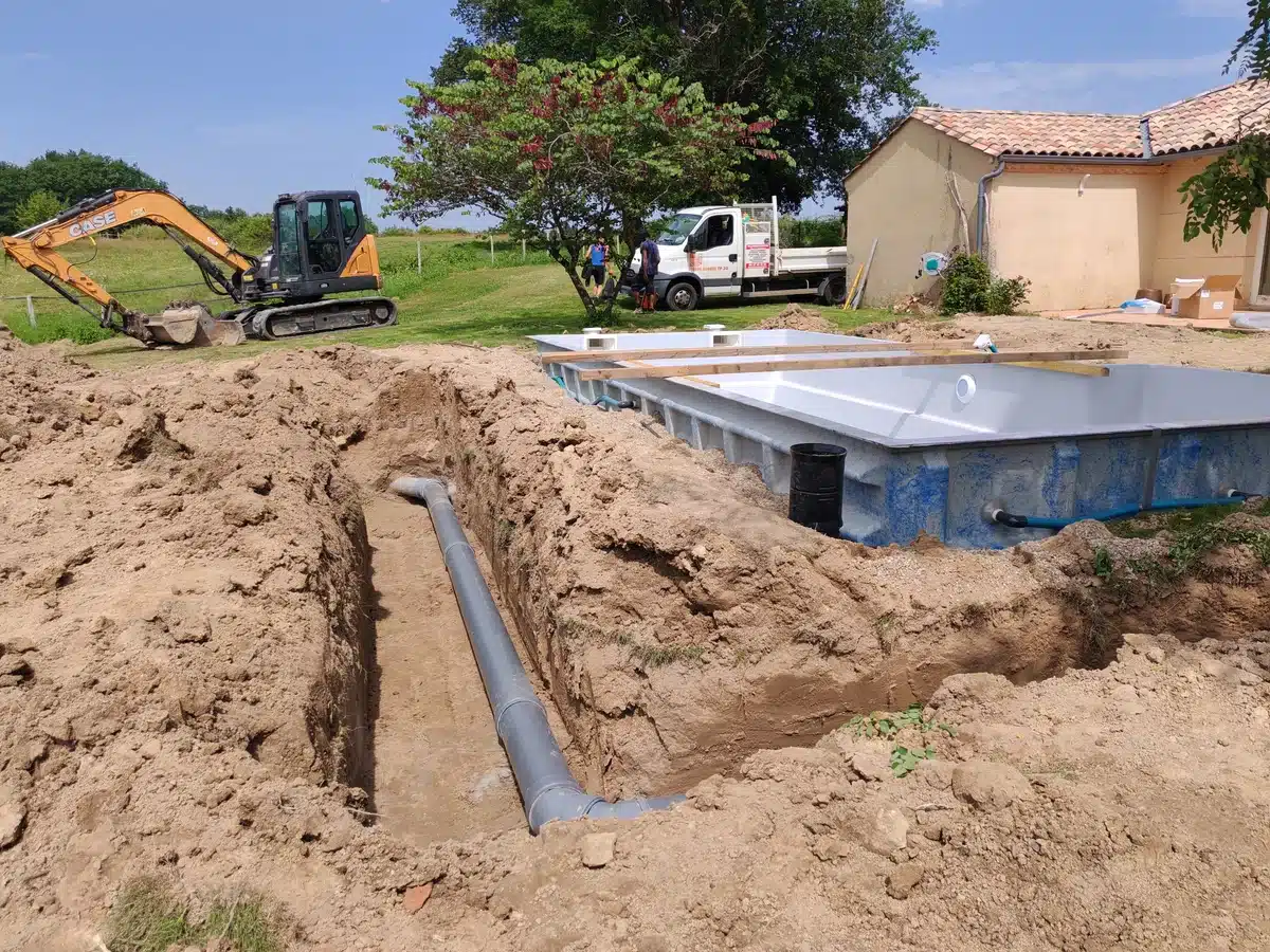 Pelleteuse Case près d'une piscine en construction, avec tranchée, tuyau et coque installée, camion TP 26.