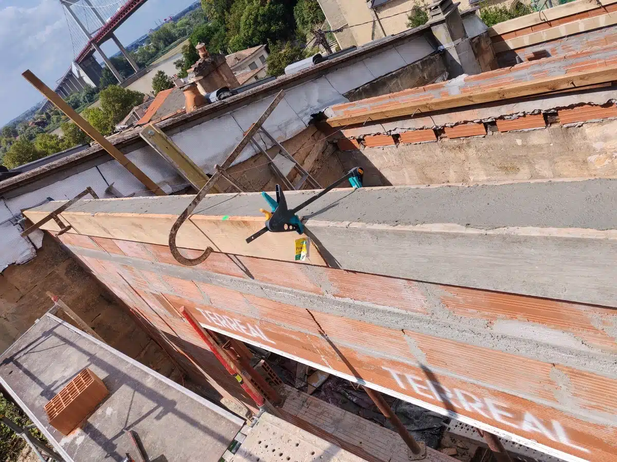Coulage de béton sur coffrage bois et briques TERREAL en rénovation. Travaux de maçonnerie, outils et pont d'Aquitaine au loin.